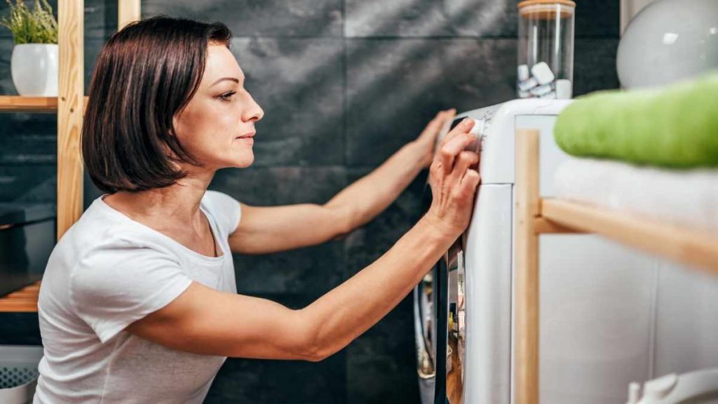 lady changing the temperature on laundry machine