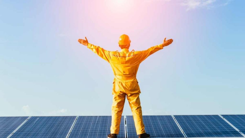 man standing on solar panels with arms in air